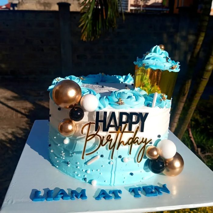 Blue birthday cake with gold and black balloon spheres — Liam at Ten
