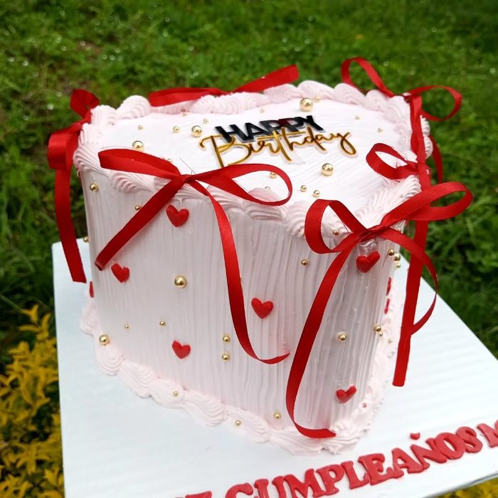 Blush pink square cake with red satin ribbon bows and fondant hearts